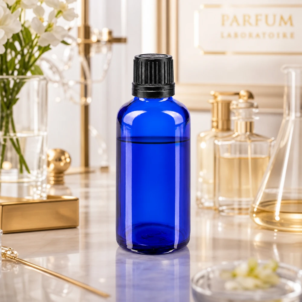 Flacon compte-gouttes bleu de 50 ml avec embout de précision de 1 mm, présenté dans un élégant décor de laboratoire de parfumerie