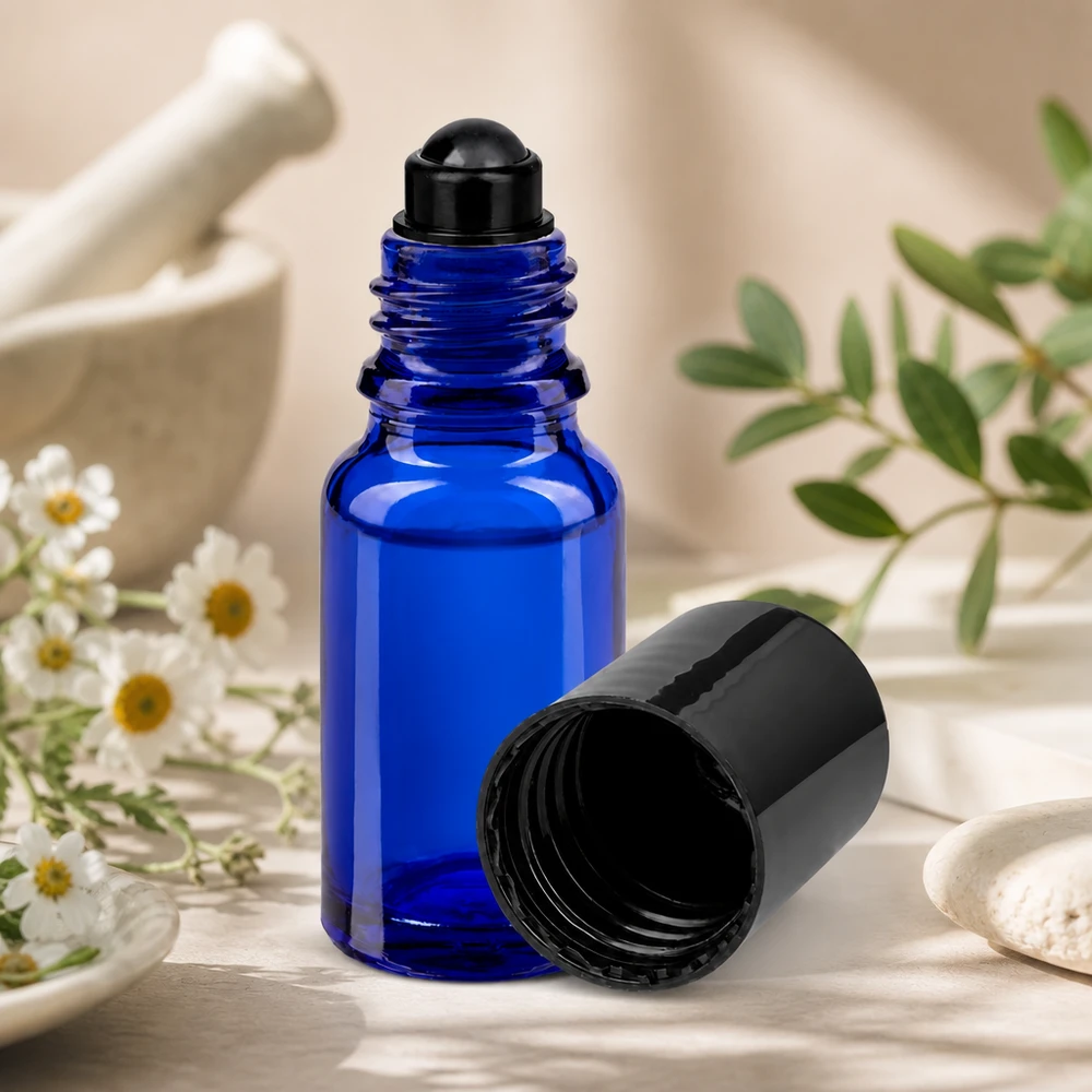 Apothekenflasche blau 10ml Roll-On Verschluss schwarz Kleine blaue 10ml Rollerflasche aus Apothekerglas neben weißen Blüten und grünen Zweigen