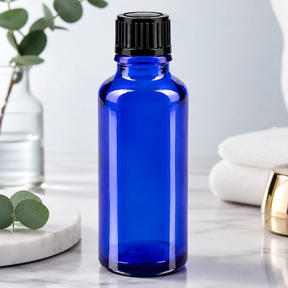 Flacon de pharmacie bleu 30ml bouchon vissable noir std Flacon en verre bleu cobalt de 30 ml avec bouchon à vis noir, posé sur une surface en marbre blanc