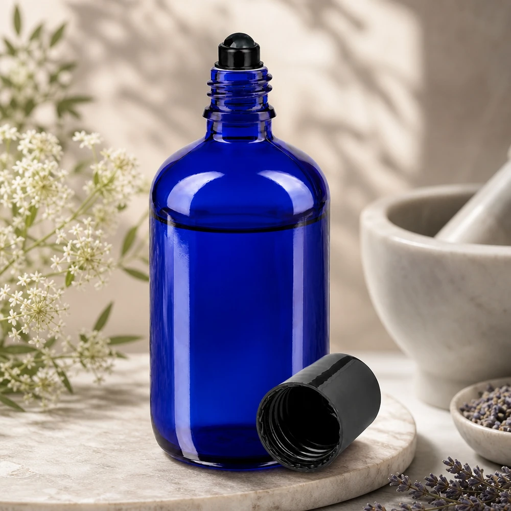 Flacon de déodorant en verre bleu 100 ml, déo à bille vide Flacon en verre bleu cobalt de 100 ml avec bille roulante noire, ouvert, posé à côté de fleurs de lavande et d'un mortier