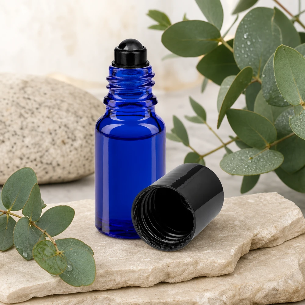 Blaue 10ml Rollerflasche aus ApoGlas mit schwarzer Rollkugel auf Naturstein vor botanischem Hintergrund