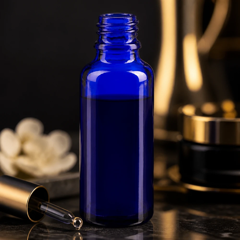 Kobaltblaue 30ml Glasflasche ApoGlas neben goldener Kosmetikverpackung und weißer Blüte