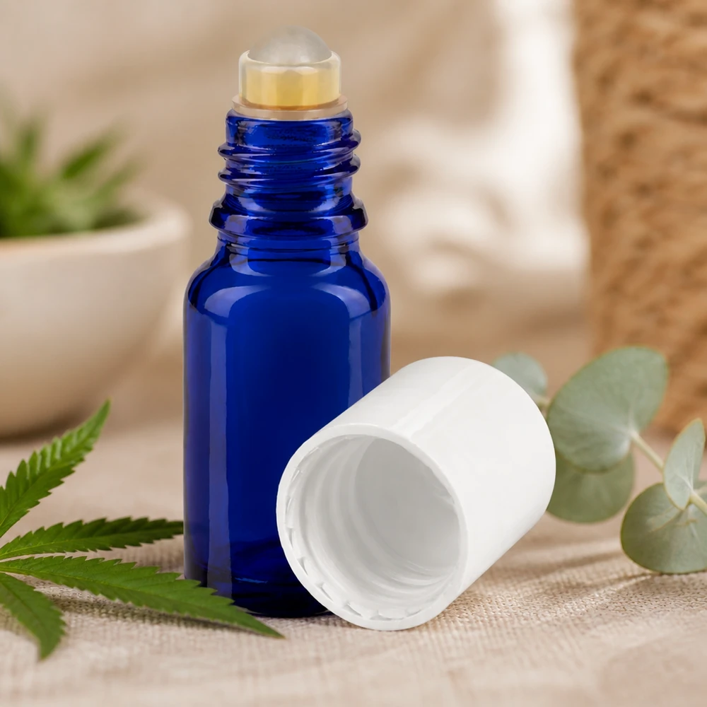 Apothekenflasche blau 10ml Roll-On Verschluss weiß Kompakte blaue Apothekerglasfl asche mit Rollapplikator zwischen frischen grünen Pflanzenblättern