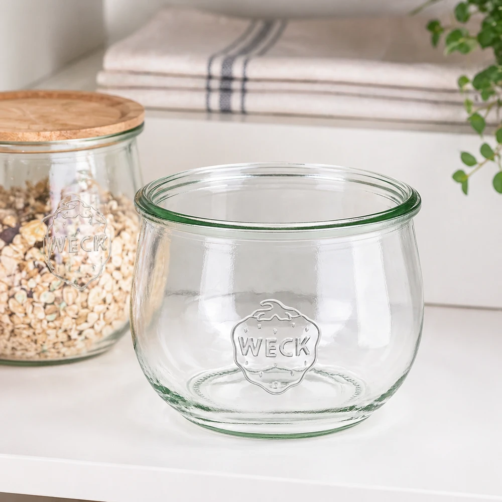 Vaso a tulipano WECK RR100 da 580 ml 580ml WECK vaso a tulipano RR100 vaso per conserve trasparente con logo su piano di lavoro bianco accanto al vaso di stoccaggio