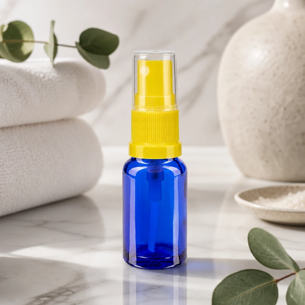 Apothekenflasche blau 30ml Sprayaufsatz gelb Zylindrische blaue Glassprayflasche 30ml ApoGlas mit gelbem Sprühkopf auf weißem Marmor