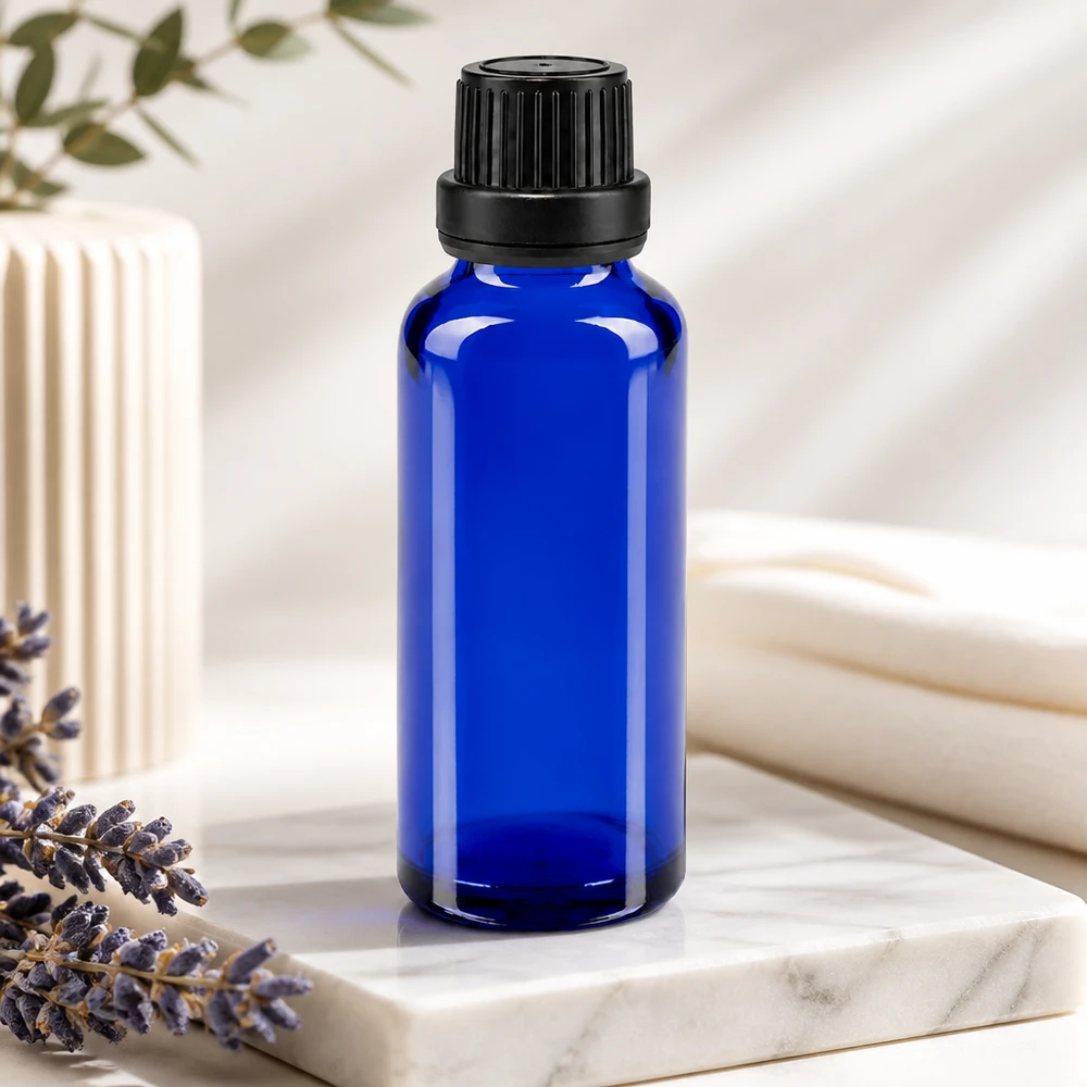 Flacon compte-gouttes ApoGlas bleu de 30 ml avec un embout de 2 mm et un bouchon noir, posé à côté d'une lavande sur du marbre
