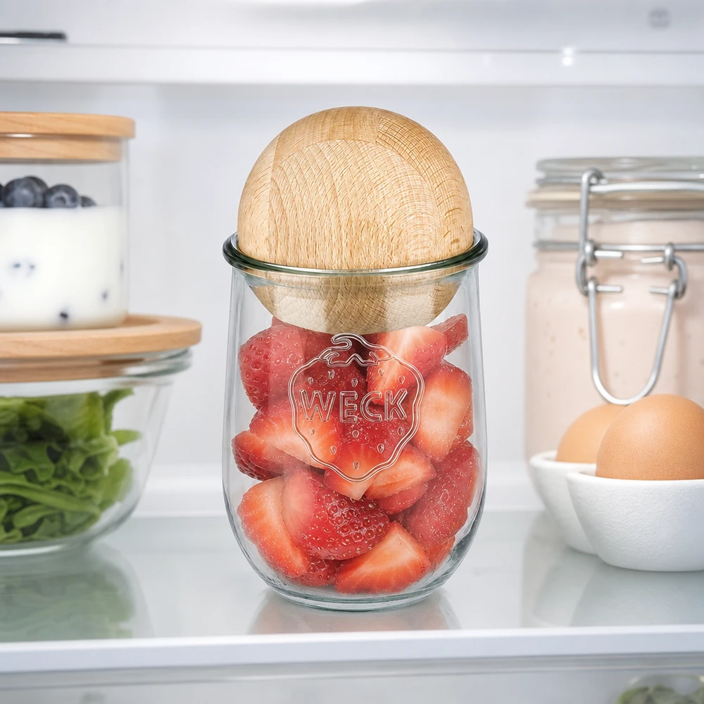 Vaso per tulipani WECK RR100 da 1062 ml con sfera in legno di faggio Il vaso a tulipano WECK 1062ml RR100 con sfera di faggio in frigorifero, riempito di fragole fresche, mostra una conservazione ottimale della freschezza.