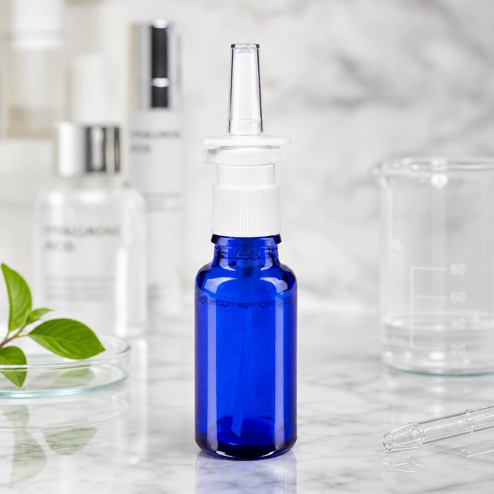 Apothekenflasche blau 20ml Nasenzerstäuber weiß Standard Arzneimittelflasche 20ml in Blauglas mit Nasenzerstäuber und transparentem Applikator auf Marmorfläche