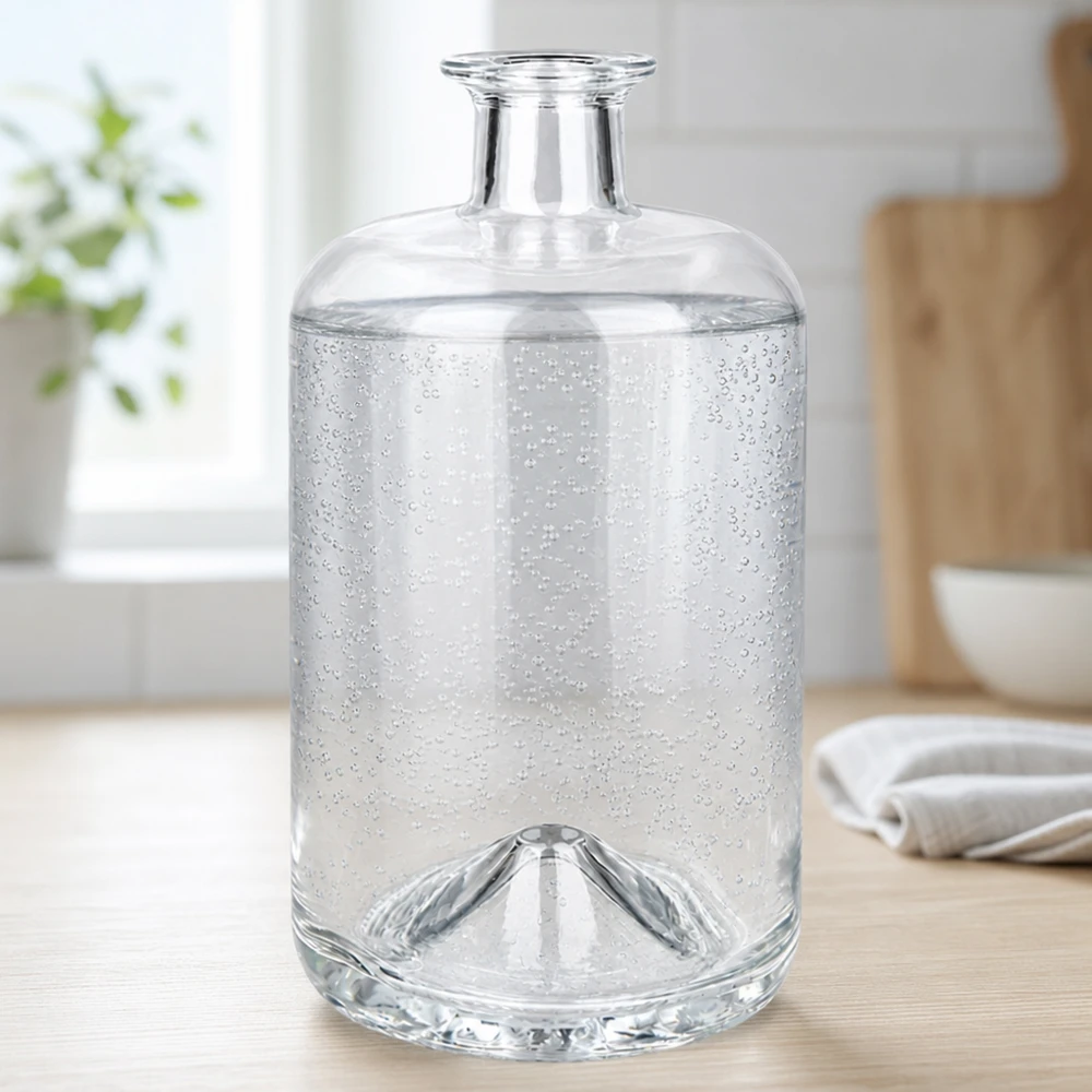 Flacone farmaceutico da 700 ml Sofia senza tappo UNiTWIST® La bottiglia di vetro Sofia da 700 ml riempita di acqua frizzante mostra le bolle di anidride carbonica in un ambiente di cucina luminoso