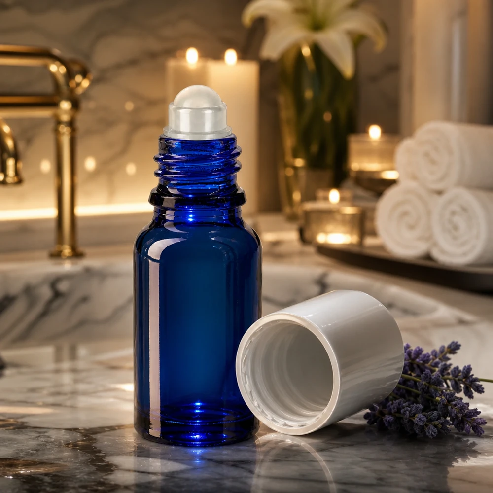 Kobaltblaue 10ml Rollerflasche mit abgenommenem weißen Deckel vor Kerzen und Handtüchern