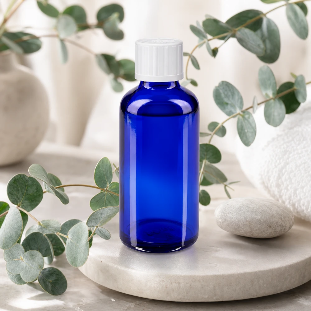Apothekenflasche blau 50ml Schraubverschluss weiß Kindersicherung Standard Apothekerglasflasche 50ml kobaltblau mit weißem Verschluss umgeben von Eukalyptuszweigen
