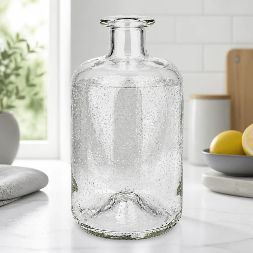 Bottiglia da farmacia Luna 500ml con texture a bolle su un piano di lavoro bianco della cucina accanto a limoni e piante