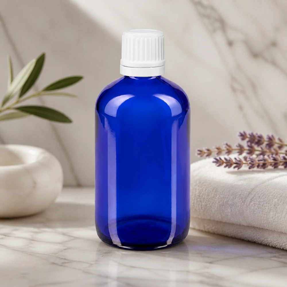 Flacon compte-gouttes bleu de 100 ml en verre d'apothicaire avec bouchon OV blanc, posé sur du marbre