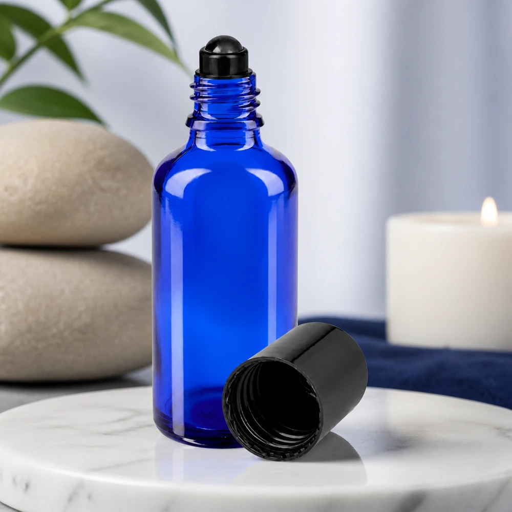 Flacon de déodorant en verre bleu 50 ml, déo à bille vide Flacon en verre bleu de 50 ml avec un applicateur à bille noir et le bouchon retiré, posé sur du marbre