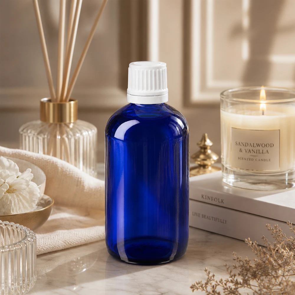 Kleine blaue Glasflasche 100ml mit weißem Sicherheitsdeckel zwischen Kerze und Bambusstäbchen