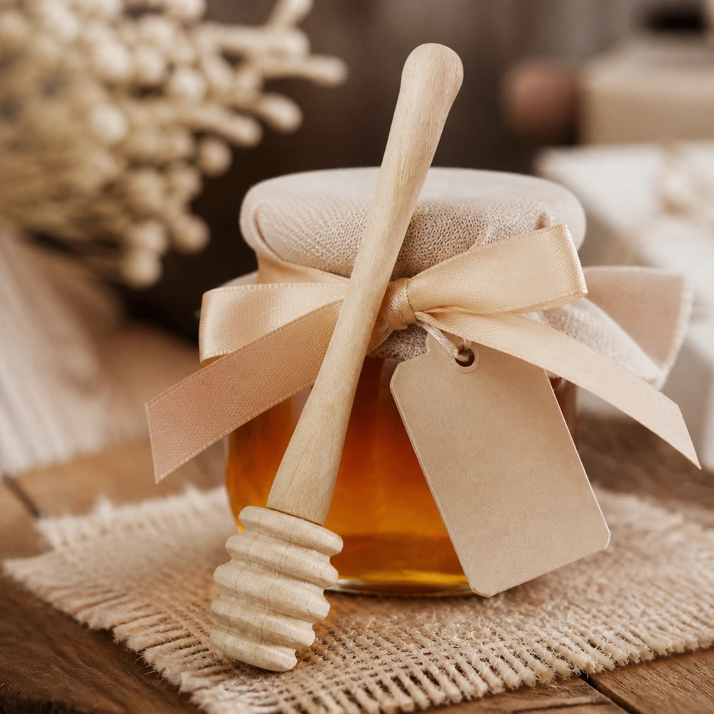 Cucchiaio da miele in robusto legno d'acero / lunghezza 10,5 cm Cucchiaio da miele in legno d'acero con confezione regalo e nastro, accanto a favi di miele su sfondo di juta