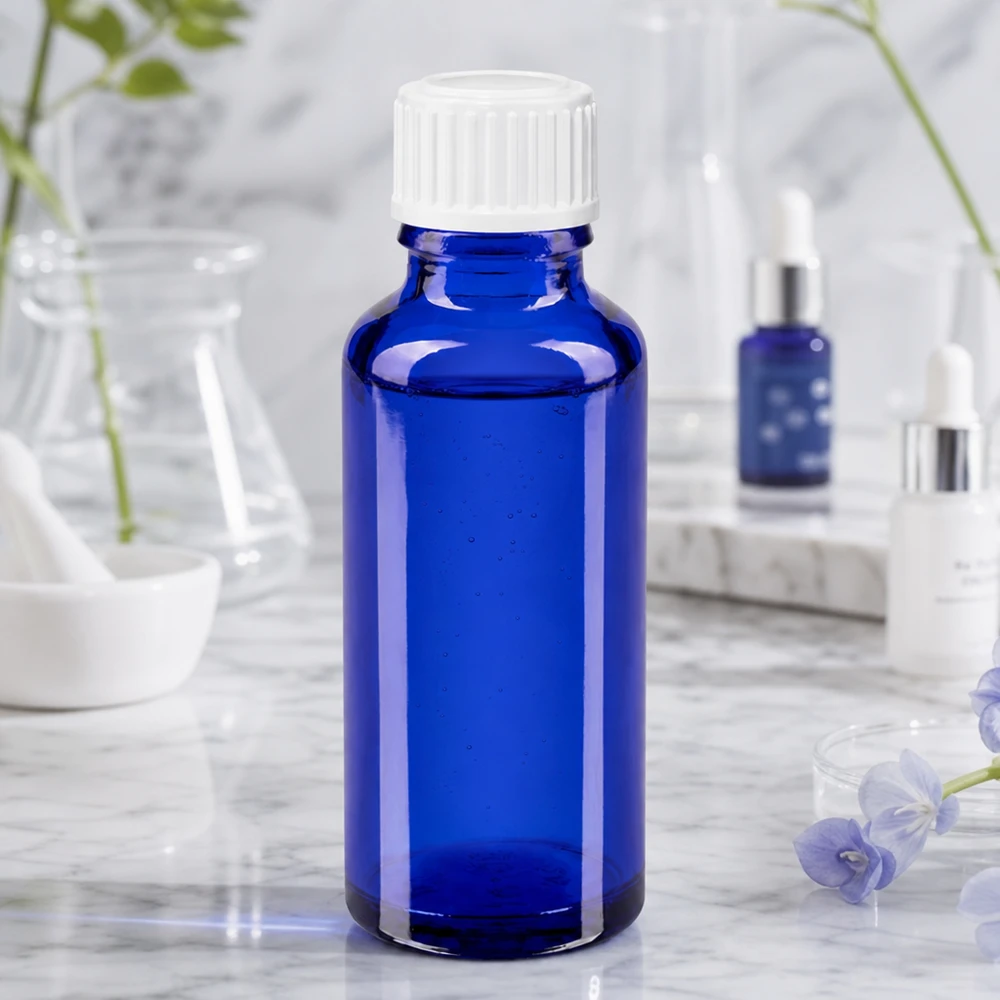 Apothekenflasche blau 30ml Schraubverschluss weiß Globuli Standard Blaues Pharmaglas 30ml mit weißem Verschluss neben Kosmetikprodukten und Glasgefäßen