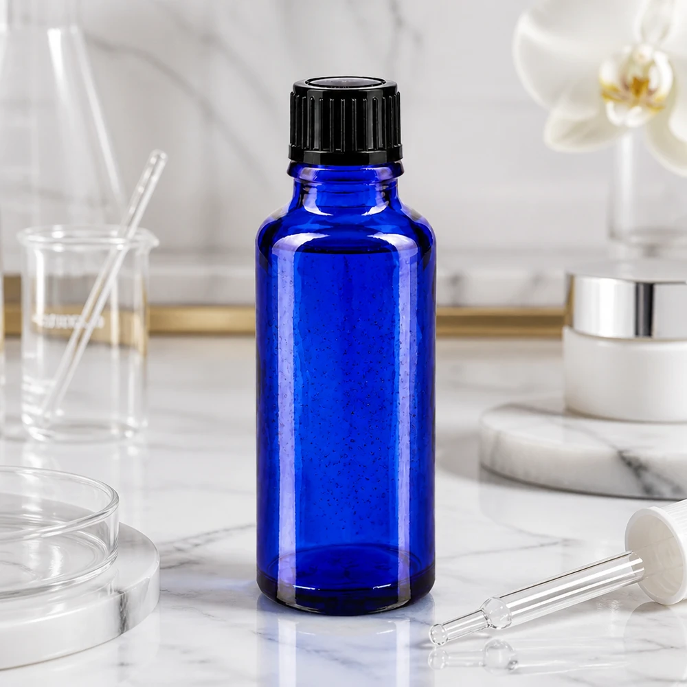 Flacon de pharmacie bleu 30ml bouchon vissable noir std Flacon en verre bleu cobalt de 30 ml avec bouchon à vis noir, posé sur du marbre blanc
