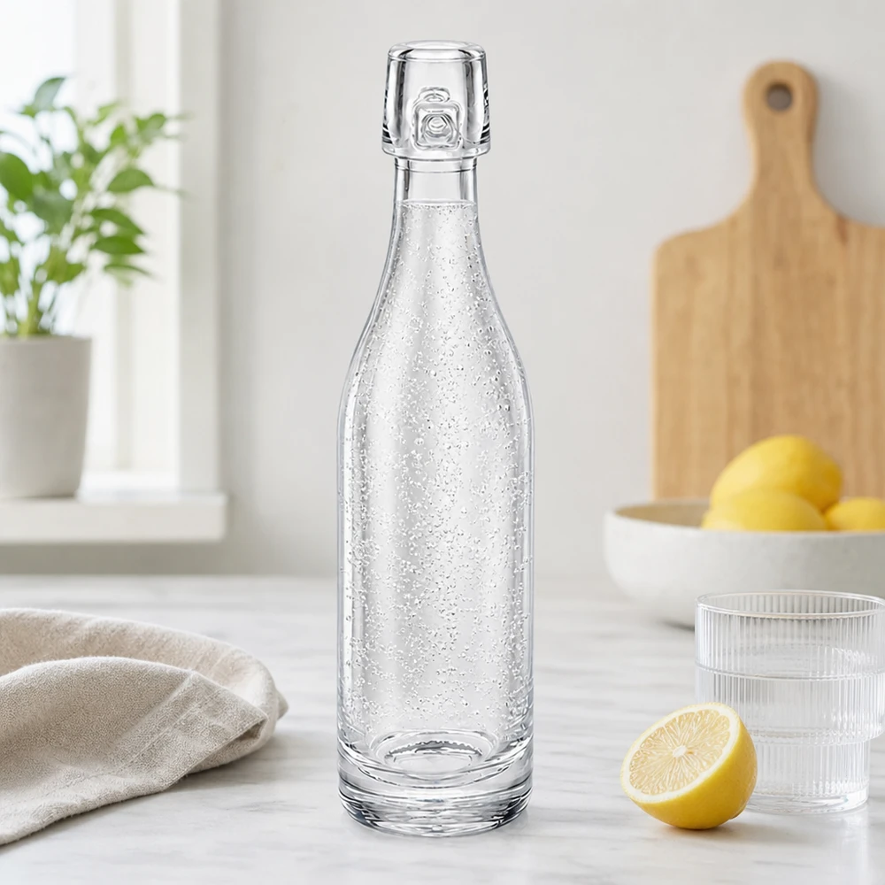 Bottiglia di vetro UNiTWIST da 50 ml riempita di acqua frizzante in una cucina moderna accanto a limoni e bicchieri piano di lavoro bianco