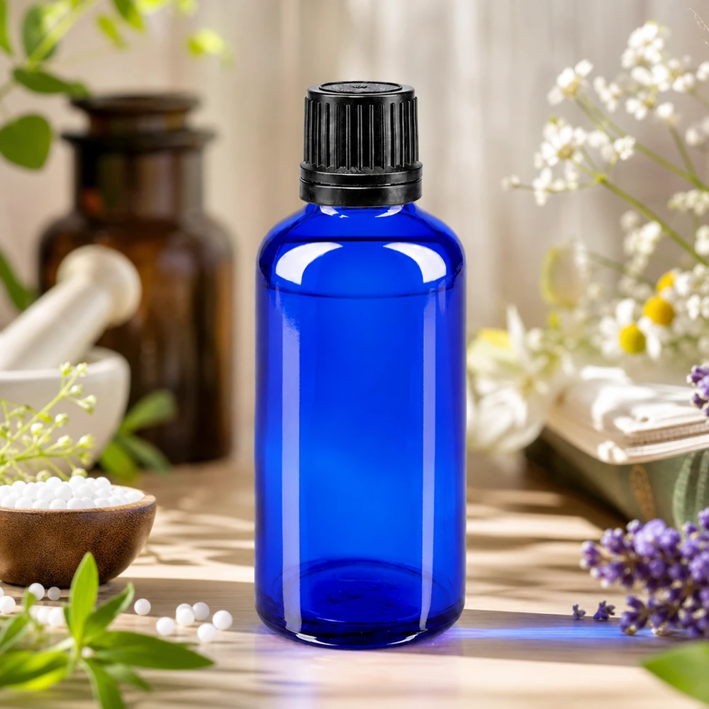 50ml kobaltblaue Apothekerflasche mit schwarzem 8mm Verschluss neben Bernsteinglas und Heilpflanzen