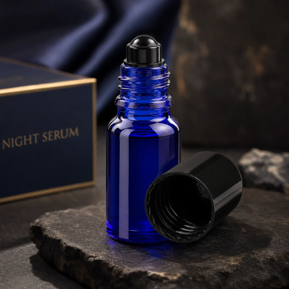 Apothekenflasche blau 10ml Roll-On Verschluss schwarz Geöffnete kobaltblaue 10ml Glasroller Flasche mit schwarzem Schraubverschluss auf dunklem Steinhintergrund