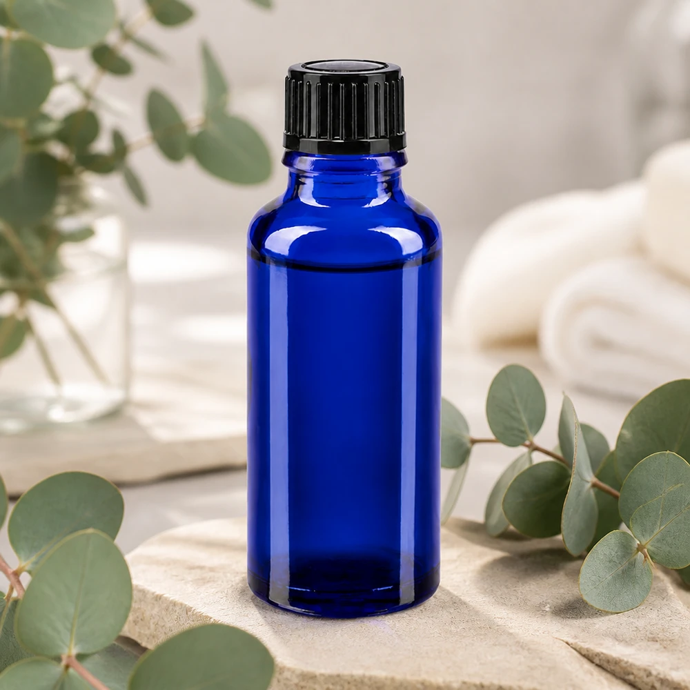 Flacon à pharmacie bleu 30ml bouchon compte-gouttes 1mm noir std Flacon en verre bleu cobalt de 30 ml muni d'un bouchon doseur noir, posé sur une pierre naturelle et orné de brindilles d'eucalyptus