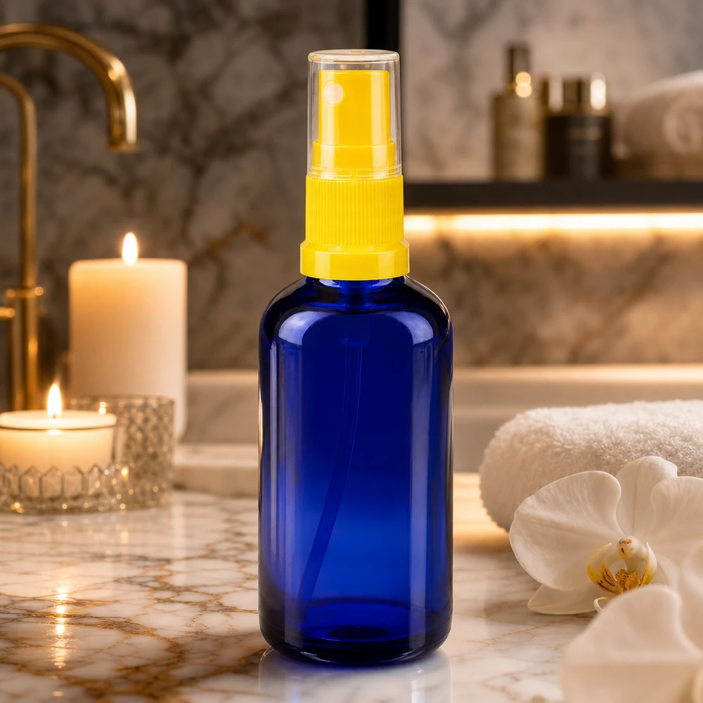 Apothekenflasche blau 50ml Sprayaufsatz gelb 50ml Blauglasflasche mit gelbem Feinnebel-Zerstäuber auf goldenem Marmorwaschtisch